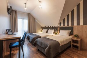 pokój z trzema łóżkami pojedynczymi położonymi obok siebie, krzesło z biurkiem