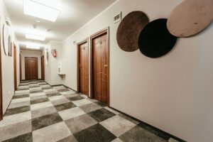 korytarz, brązowe drzwi do pokoi, dekoracje na ścianie