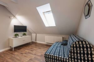 biało-czarna kanapa, przed nią biała szafka i telewizor