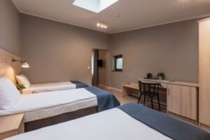 pokój z trzema łóżkami i biurkiem