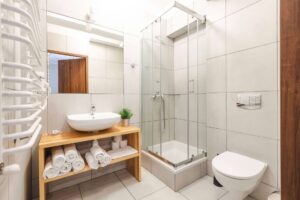 łazienka z prysznicem, zwinięte ręczniki na szafce pod umywalką